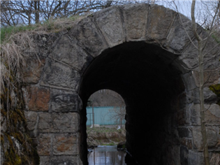 Zaklenutý mostek pod bývalým železničním náspem